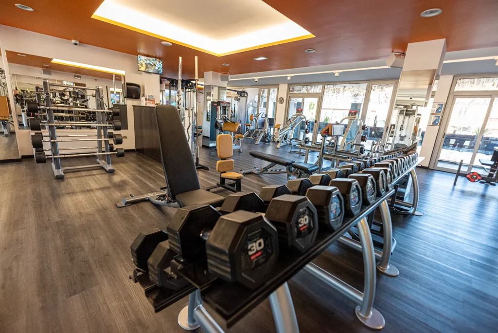 Sala cardio con ellittiche e rastrelliera di manubri nella palestra di Perugia